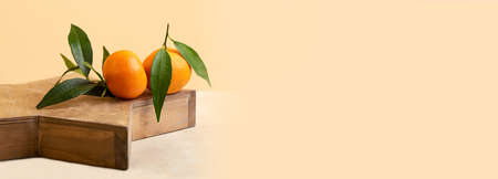 Composition from the fresh mandarins with green leaf on the wooden tray.Isometric beige background.Concept of the Christmas or family celebration.Copy space for text,large banner.の写真素材