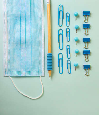 Composition from different school supplies on the blue background and medical mask.Back to school concept,top view.の写真素材