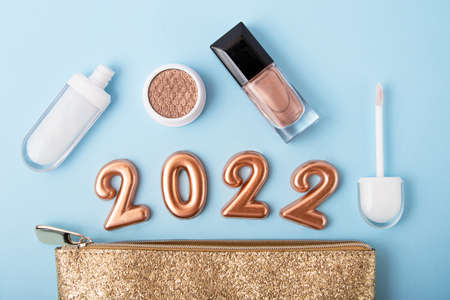 Top view of golden cosmetics bag and makeup accessories around, festive concept.