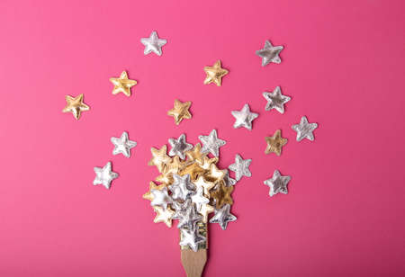 Top view of the wooden brush on the pink background, with silver and golden stars above.