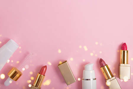 Top view of cosmetics containers and lipstick on pink background with shihing bokeh.Festive flat lay with copy space.の写真素材