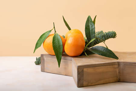 Composition from the fresh mandarins with green leaf on the wooden tray.Isometric beige...
