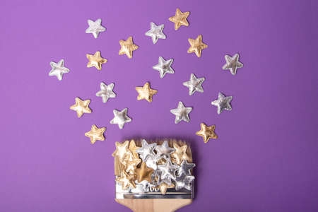 Top view of the wooden brush on the violet background,with silver and golden stars above.Greeting...