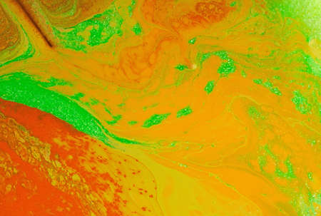 Beautiful liquid texture of the nail polish.Orange,green,yellow colors.Background with copy space.Fluid art,pour painting technique.Good as digital decor.の写真素材