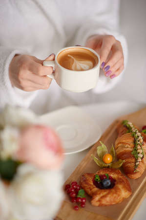 Woman hold cup of coffee,tasty bakery near. good as mockup.の写真素材