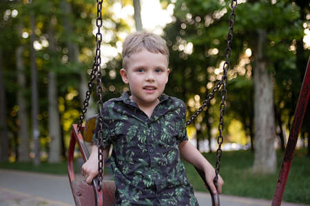 Smiling preschooler riding on swing at the park.の写真素材