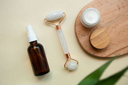 Top view of facial roller for massage on wooden slice.Pastel colors,eco friendly concept.の写真素材