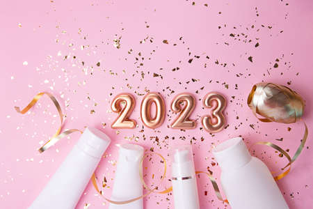 Top view of the cosmetics containers on pink background.Rose gold numbers 2023 above.Good for new year offer and text overlay.の写真素材