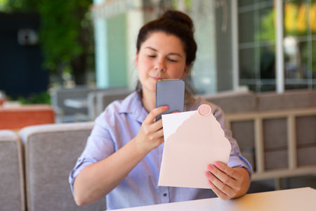 Closeup photography of woman,making photography of invitation envelope with wax seal and blank card.の写真素材