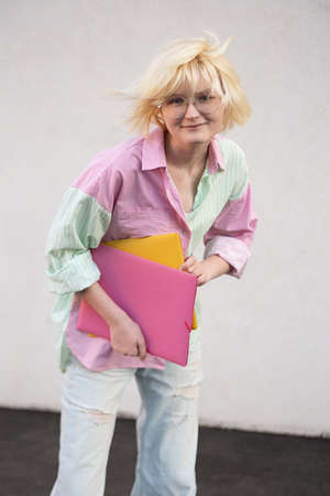 Funny teenage girl student with folders on the neutral background.の写真素材