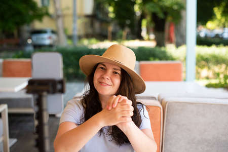 Attractive woman outside sitting with tripod and smartphone, making video call or providing online lesson.の写真素材