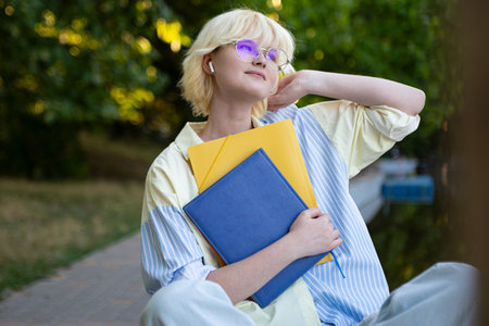 Teenage girl in glasses with colorful folders outside.Closeup portrait.の写真素材