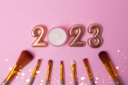 Top view of the makeup brushes on pink background.Rose gold numbers 2023 above.Good for new year offer and text overlay.の写真素材