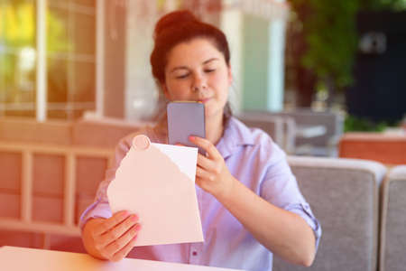 Closeup photography of woman,making photography of invitation envelope with wax seal and blank card,sunlight on background.の写真素材