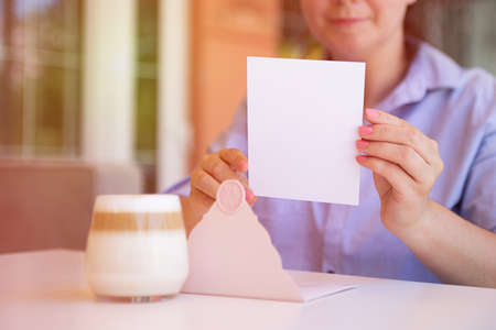 Closeup photography of anonymous woman,holding blank certificate gift certificate gift outside.Sunlight on background.の写真素材
