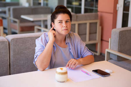 Bussines woman sitting outside with her mobile phone and blank document with wireless headphone.の写真素材