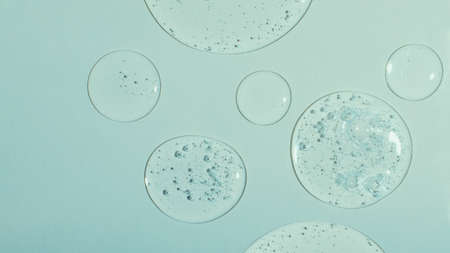 Top view of liquid cosmetics gel with bubbly structure on pastel cyan background,large banner.