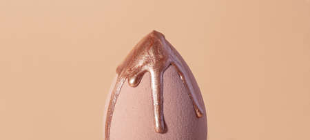 Closeup photography of beauty blender with dripping bronzer on it.Neutral beige background.の写真素材