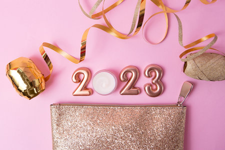 Top view of rose gold numbers 2023 and face cream from above,golden cosmetic bag near it.Good for new year offer and text overlay.の写真素材