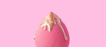 Closeup photography of beauty blender with dripping bronzer on it.Neutral pink background.の写真素材