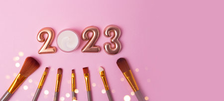 Top view of the makeup brushes on pink background.Rose gold numbers 2023 above.Good for new year offer and text overlay,large banner with copy space.の写真素材