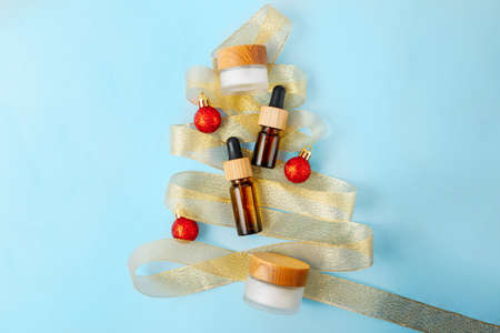 Composition from zero waste cosmetics containers,view from above.Golden ribbon lies like christmas tree and red balls around.の写真素材