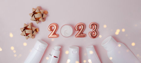 Top view of the cosmetics containers on gray background.Rose gold numbers 2023 above.Good for new year offer and text overlay.の写真素材
