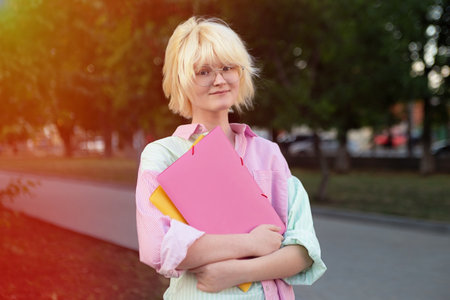 Horizontal photography of teenage girl student staying outside,sunlight on background.の写真素材