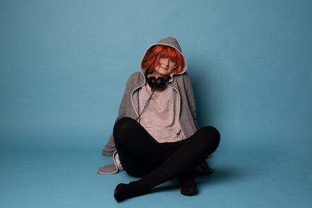 Stylish teenage girl with headphones on blue background.の写真素材