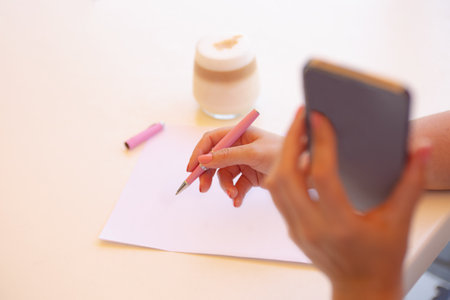 Closeup photography from above of female hand,signing document outside.Coffee cup near her.