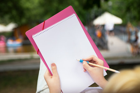 Anonymous girl making notes or drawing in the blank paper book.の写真素材