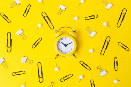 Top view of yellow oclock with black and white stationery around.Back to school concept.