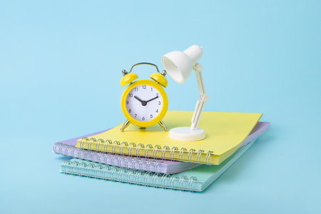 Bright yellow oclock and white lamp staying on top of notebooks in pastel colors.Back to school concept.の写真素材