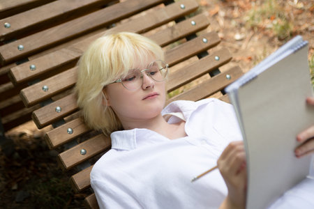 Top view of female student, making notes at the notebook.の写真素材