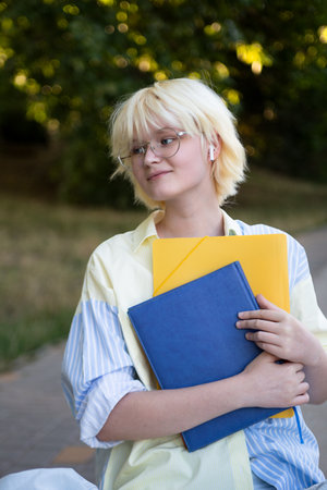 Cheerful teenage girl with yellow and blue folders and notebook in hands.Vertical photography.の写真素材