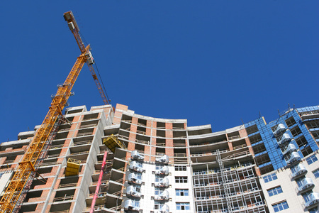 Crane and building construction site against blue skyのeditorial素材