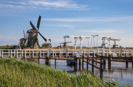 Traditional dutch windmills and wooden drawbridge reflected in the water surface of the canal. Outdoor scene in famous Dutch village Kinderdijk, Hollandの写真素材