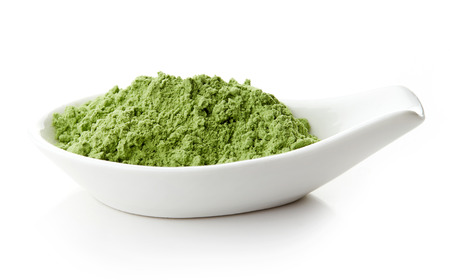 Young barley or wheat grass in white porcelain spoon on white backgroundの写真素材