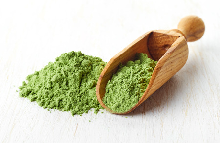 Young barley or wheat grass with wooden shovel, detox superfood, white backgroundの写真素材