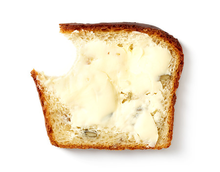 Butter spread on sliced healthy grain bread isolated on white background, top view