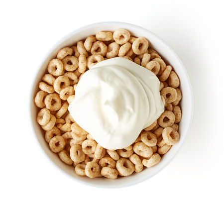 Bowl of Whole Grain Cheerios Cereal and yogurt isolated on white background, top view
