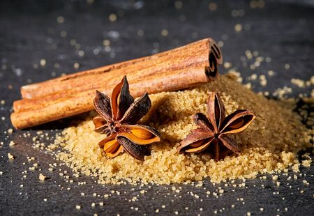 Heap of brown sugar, cinnamon sticks and star anise on stone tableの写真素材