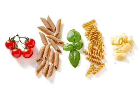 Penne and fusilli pasta, tomato, basil and cheese isolated on white backgroundの写真素材