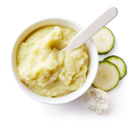 Cauliflower and zucchini baby puree in round dish with baby spoon isolated on white background, top viewの写真素材