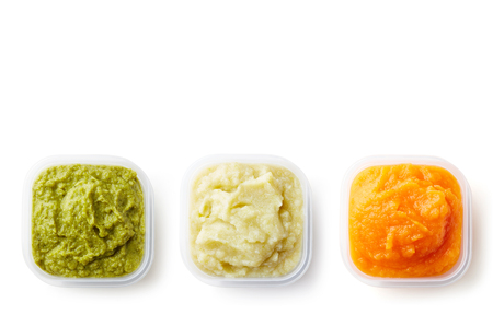 Green, yellow and orange baby puree in plastic containers isolated on white background, top viewの写真素材