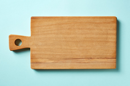 Wooden cutting board on blue background, top viewの写真素材