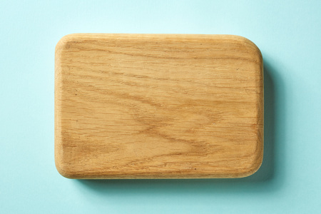 Wooden cutting board on blue background, top view
