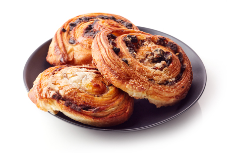 Freshly baked sweet buns on black plate isolated on white backgroundの写真素材