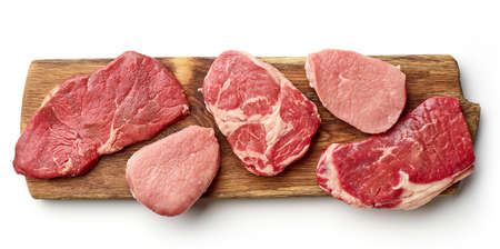 Variety of steaks on wooden cutting board - strip loin, entrecote, rump steak, beef filet, isolated on white background, top viewの写真素材