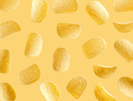 Salted potato based chips flying in the air on yellow backgroundの写真素材